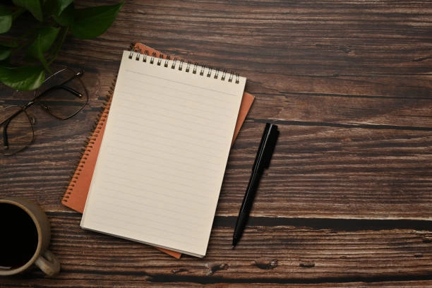 Open notebook with handwritten notes beside a printed housing listing on a pale wooden table, a pencil and paper clip resting on the margin, soft daylight from a side window, 1200x800